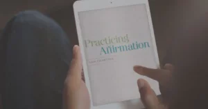 A person holding a tablet with an e-book opened to the title page reading "Practicing Affirmation" by Sam Crabtree.