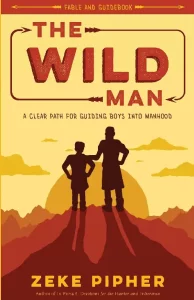 Book cover of "The Wild Man: A Clear Path for Guiding Boys into Manhood" by Zeke Pipher. It features silhouettes of a boy and an adult man standing on a mountain peak against a sunset, with red and yellow tones dominating the background.