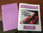 A pink sheet titled "Book-at-a-Time Bible Reading Plan" alongside a brochure for "Lanse Evangelical Free Church" featuring the phrase "Read Through the Bible in 2025," showcasing a partially open Bible and colored markers.