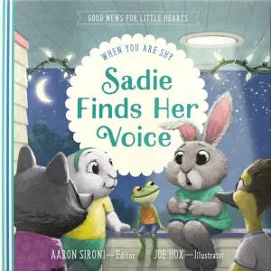 Cover of the children's book "Sadie Finds Her Voice," featuring a group of friendly, anthropomorphic animals gathering at night. The central character, Sadie, is a grey bunny in a turquoise dress, surrounded by a frog, a raccoon, a dog, and a bird, all looking engaged and supportive. The scene is adorned with string lights and a crescent moon, creating a warm and inviting atmosphere. The book addresses the theme of shyness and is part of the "Good News for Little Hearts" series. Edited by Aaron Sironi and illustrated by Joe Hox.